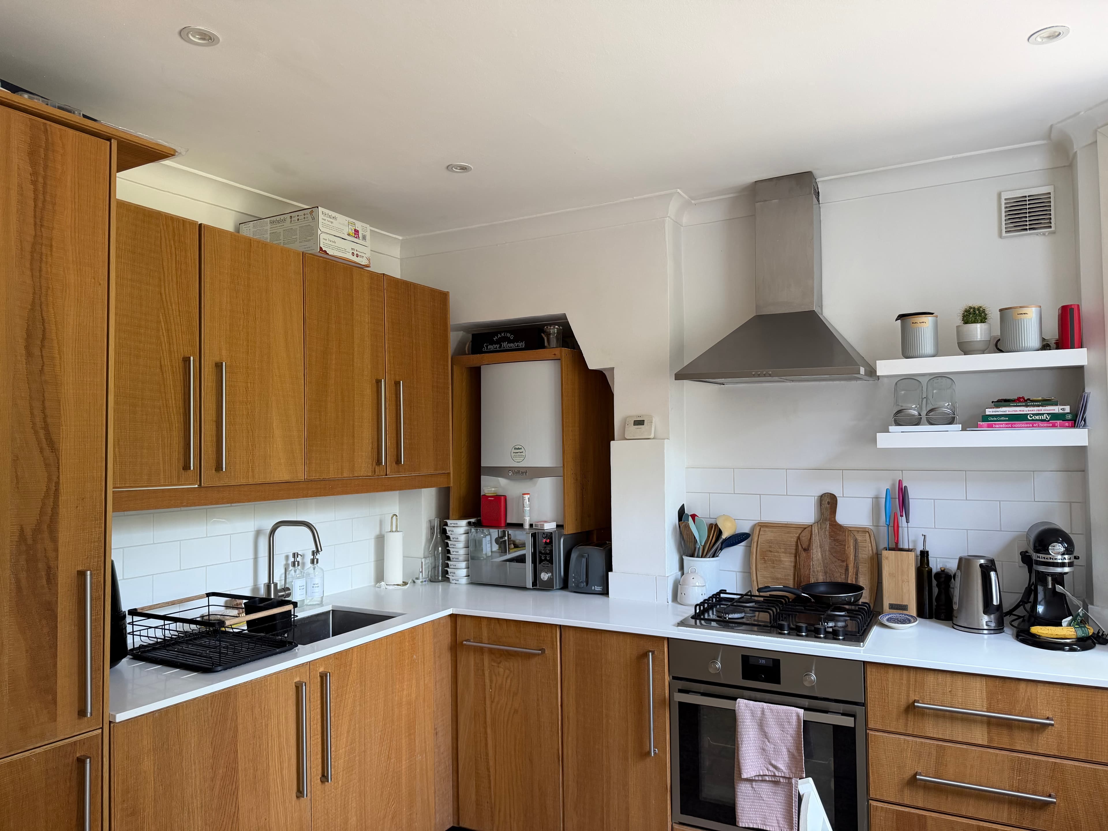 Modern kitchen with light wood cabinets, white countertops, stainless steel appliances, and subway tile backsplash.